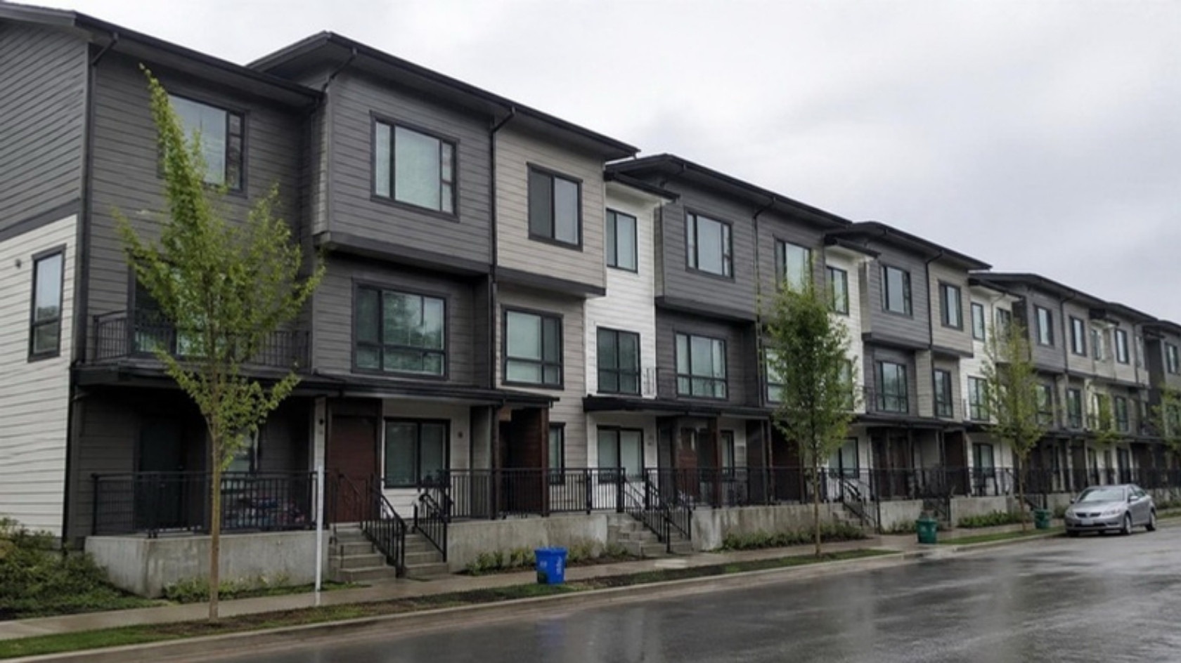 Row of three-storey townhomes on a wet street
