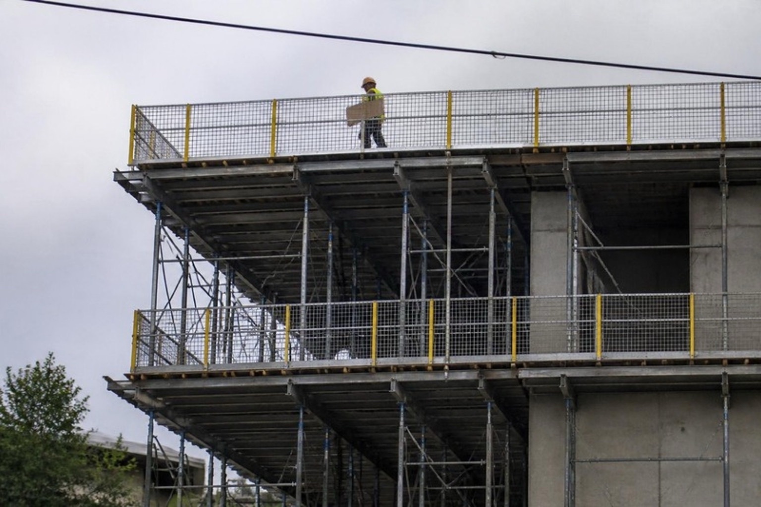 Two levels of suspended slab formwork with guardrails and shoring frames at the edge of a concrete building